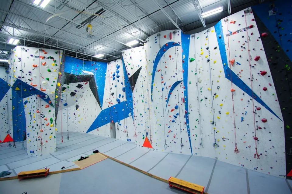 Tall white roped walls with blue features and hanging ropes at Junction Climbing Centre, London, Ontario
