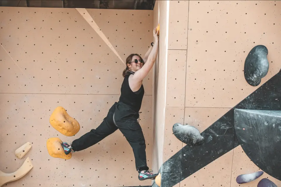 Climber bridging across a corner on the outdoor bouldering wall