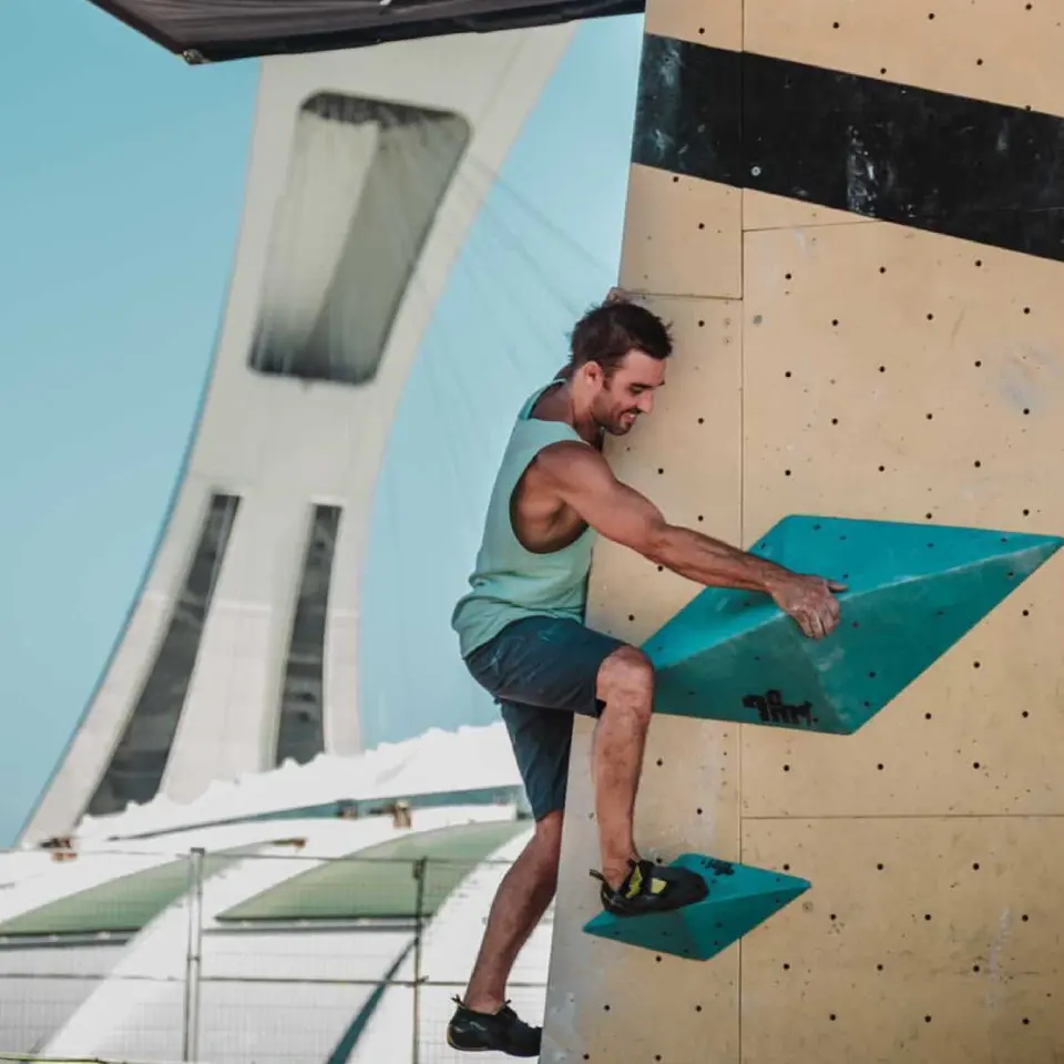 Climber on the outdoor wall with the Olympic Stadium tower behind