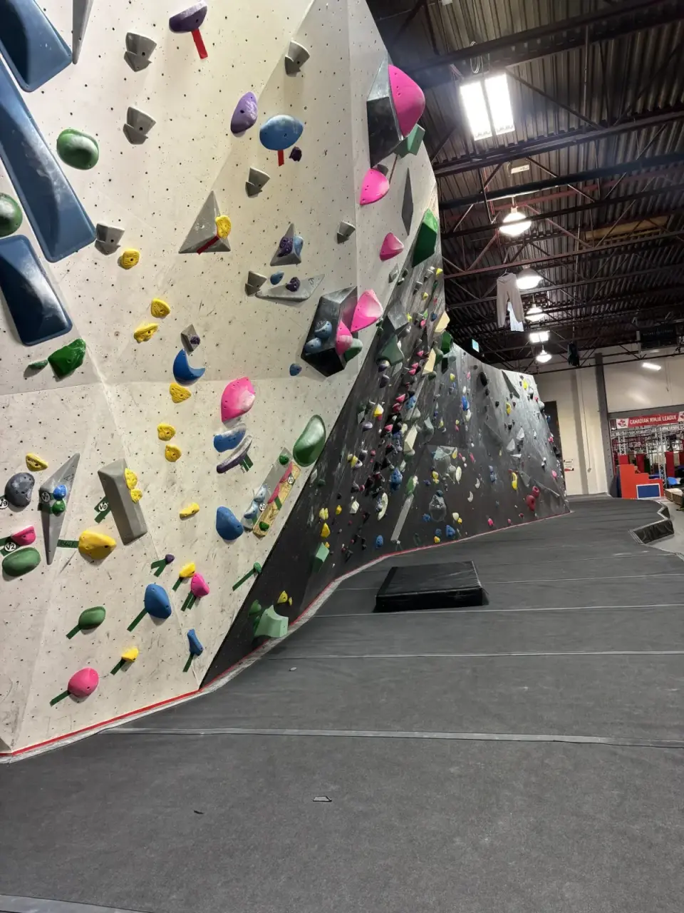 Long bouldering wall with graded problems and padded flooring