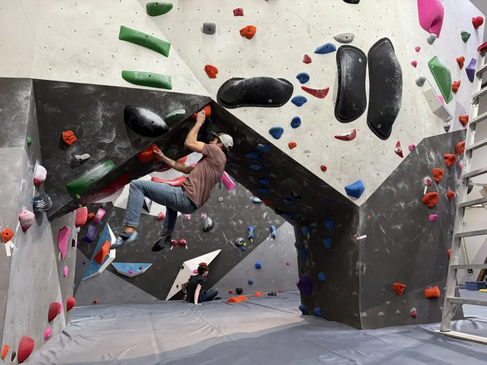 Climber pulling through an overhanging arch on the bouldering wall