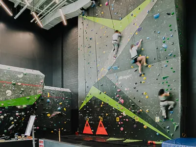 Three climbers on the auto-belay wall beside the bouldering wall