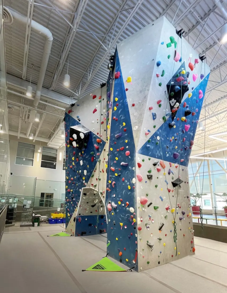 Full height of the four-storey climbing wall, with angled volumes and ropes hanging from the top