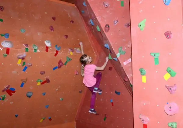 Young climber on the angled red walls of the indoor climbing cave