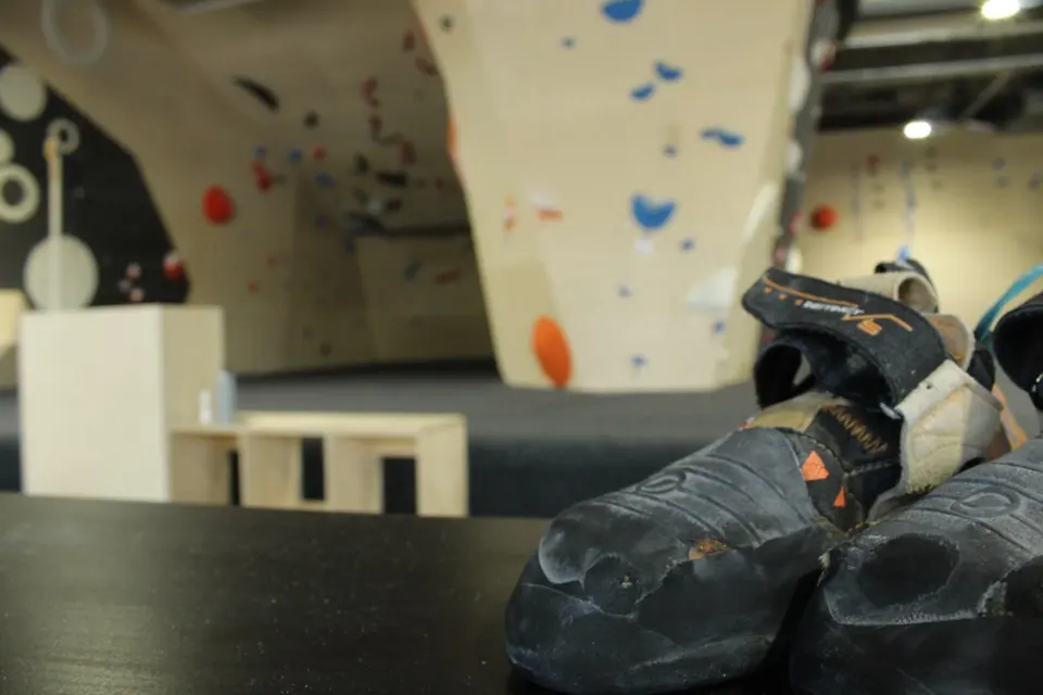 Worn climbing shoes on a bench in front of the bouldering walls