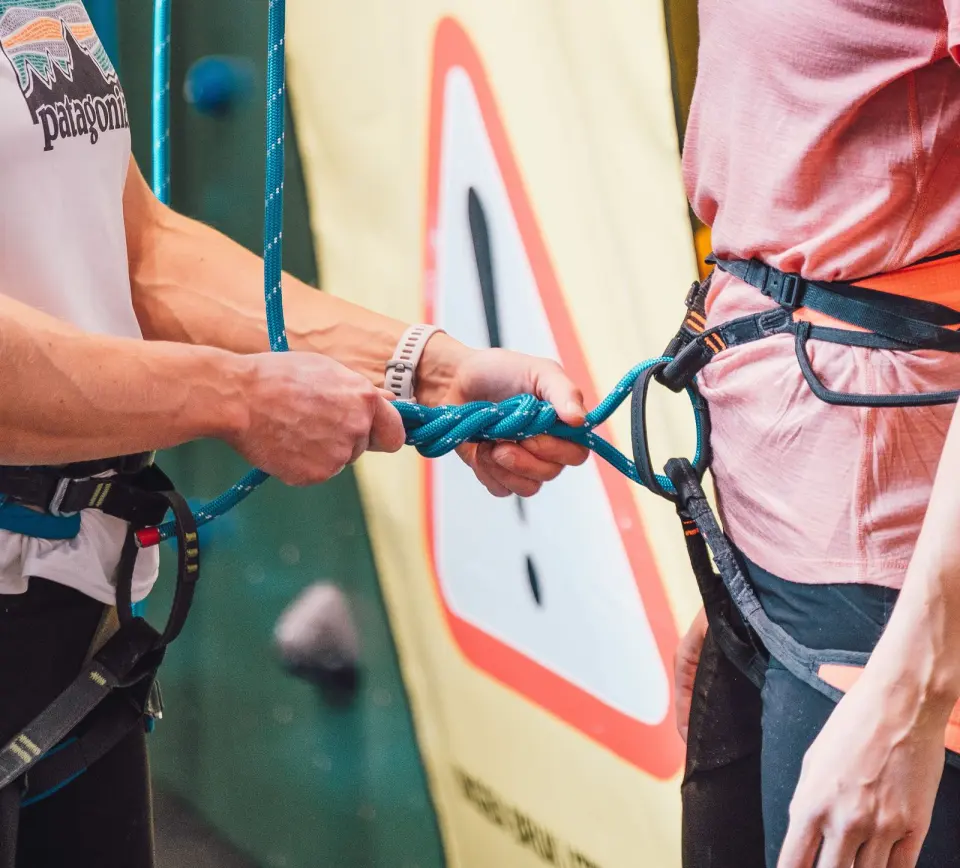 Partner checking the figure-eight knot tied into a climber's harness