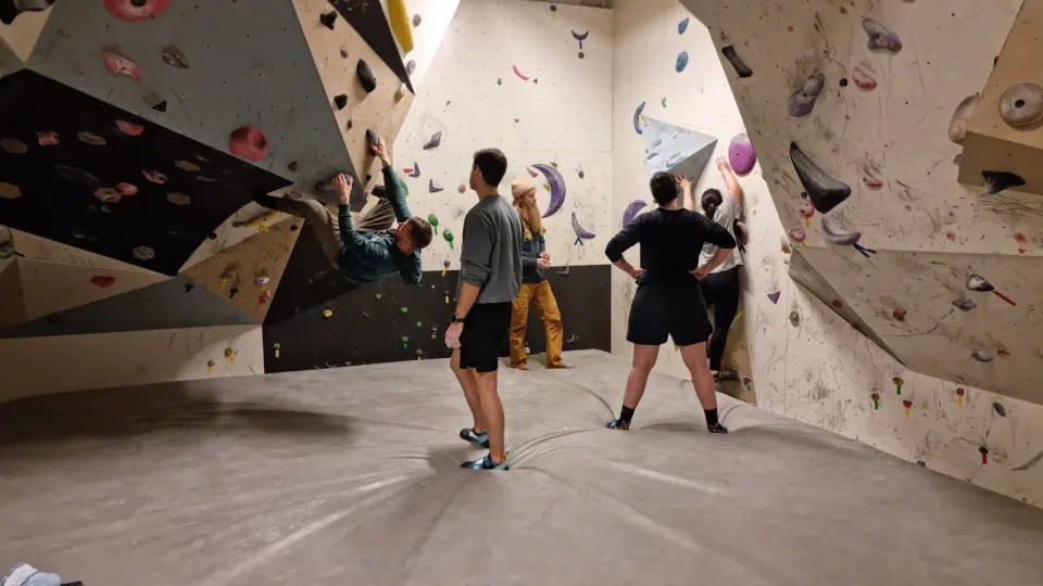 Climbers on the padded floor of the bouldering room, one on an overhang