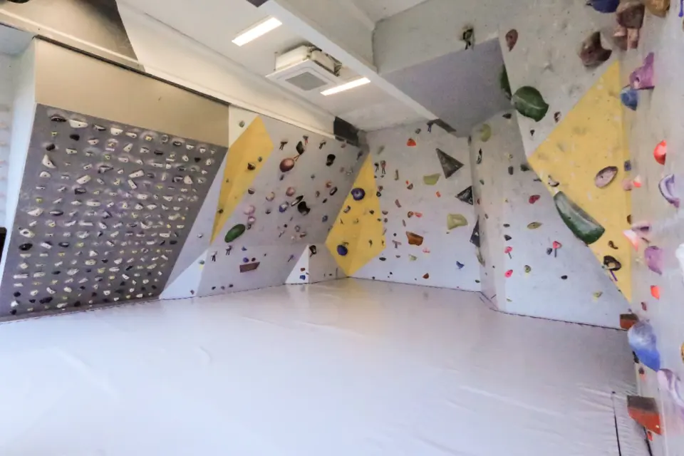 Bouldering room with angled walls, yellow volumes and a steep board covered in holds
