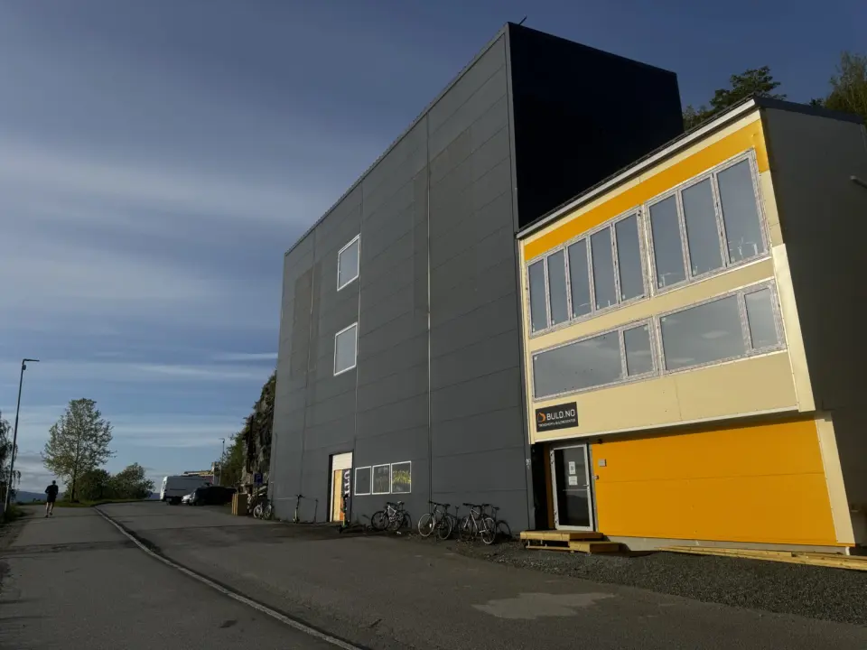 The tall grey hall and yellow entrance building of the bouldering centre in evening sun
