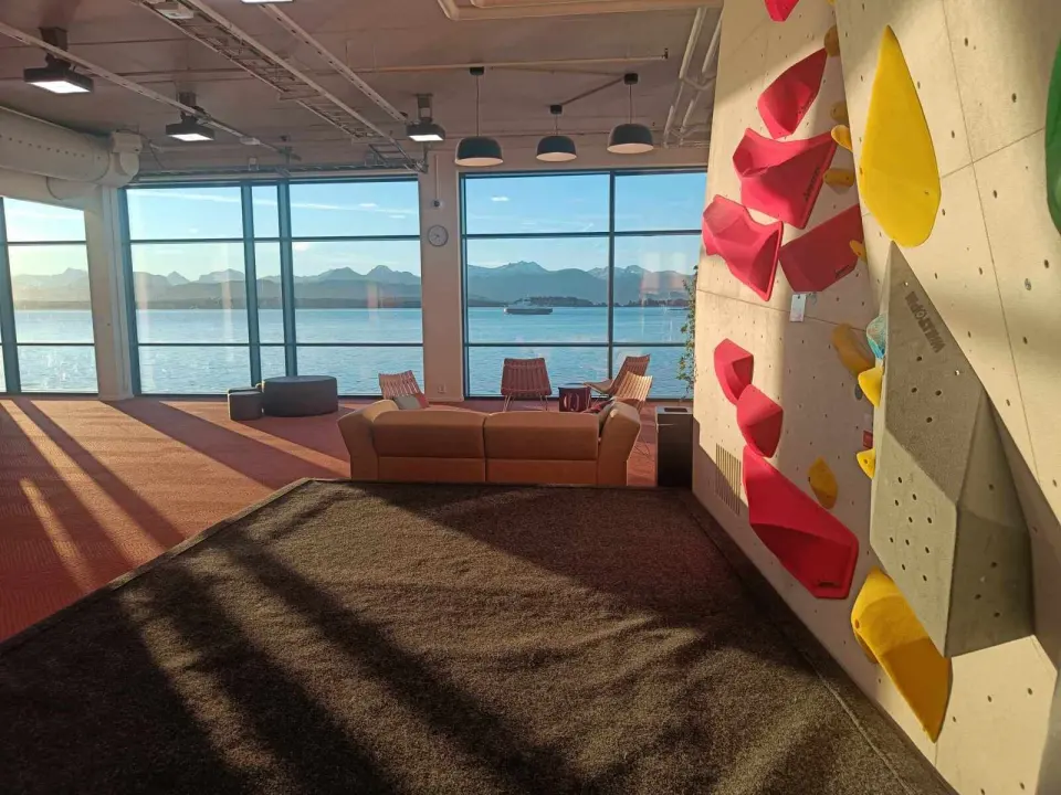 Bouldering wall beside a lounge with large windows looking over the fjord