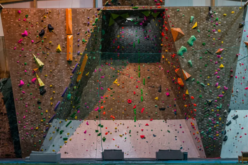 Tall rope-climbing walls in a sports hall, with an overhanging central section