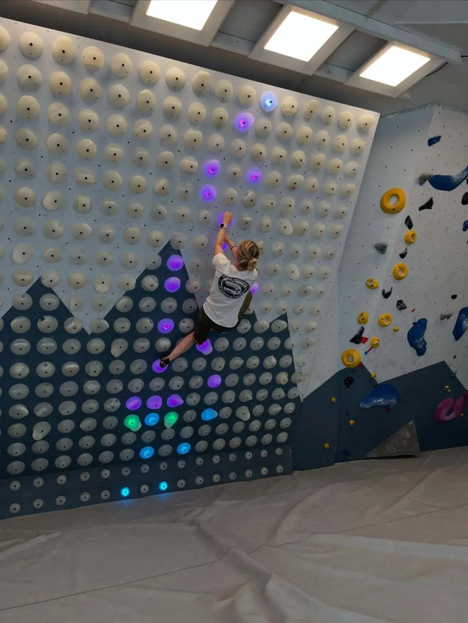 Climber reaching up a lit problem on the system board
