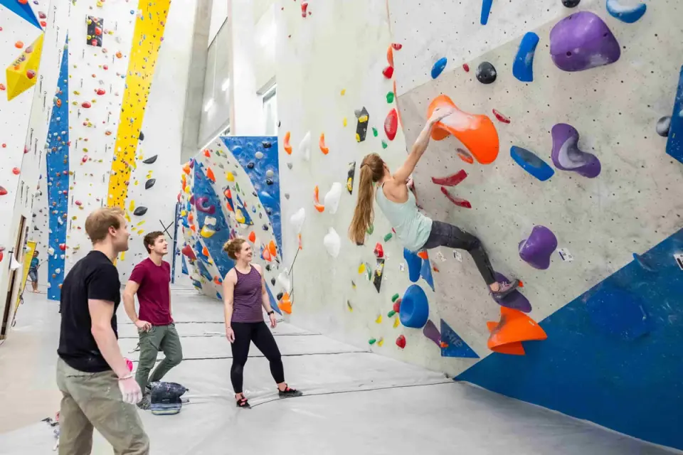 Climber on a bouldering wall with the tall rope-climbing walls behind