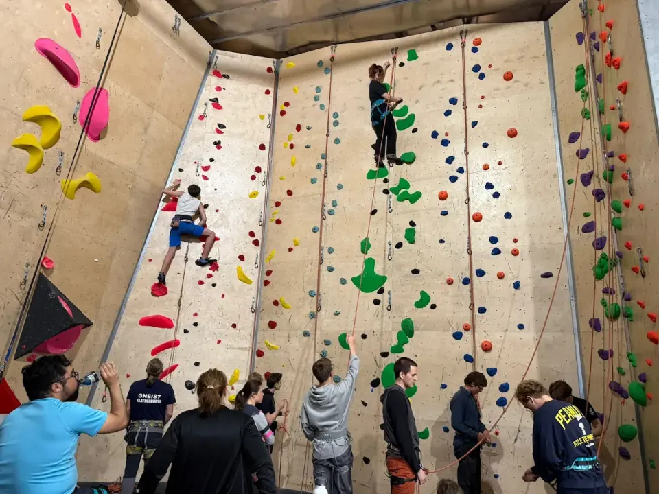 Climbers on tall rope walls with belayers on the ground below