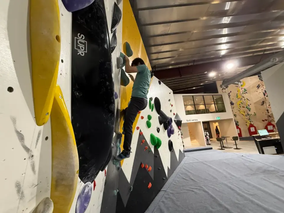 Climber on a bouldering wall with big yellow and black volumes