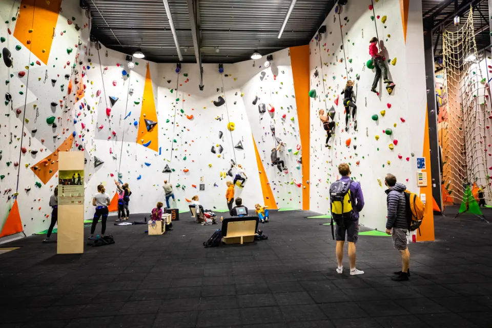 Horseshoe of tall white auto-belay walls with climbers on several routes