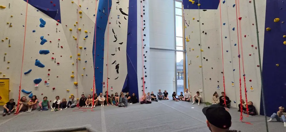 Rope walls with blue and white panels and hanging ropes, with people sitting along the base