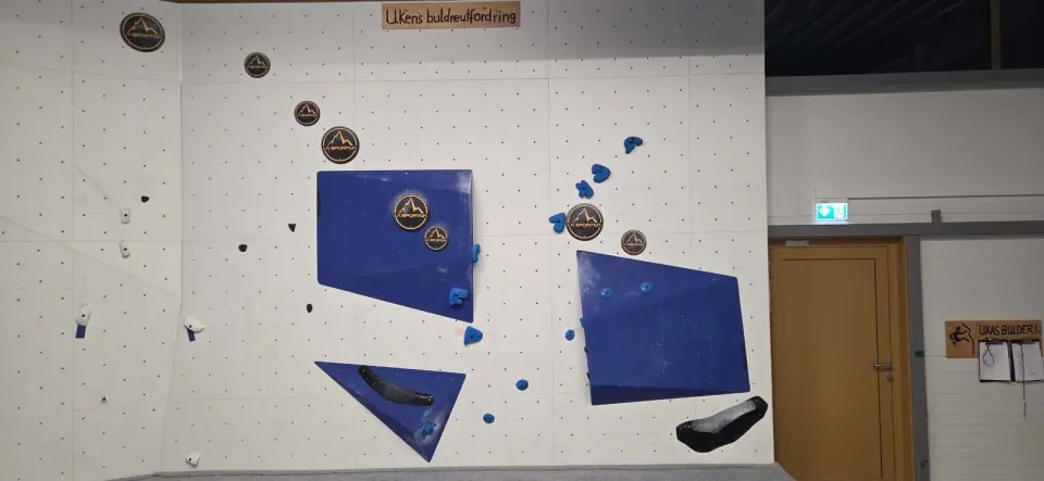 Bouldering wall with blue volumes and the weekly boulder challenge sign