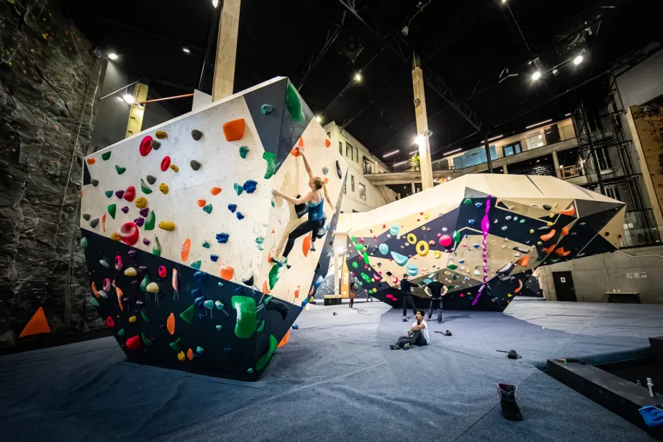 Climber on a large free-standing boulder in a high-ceilinged bouldering hall