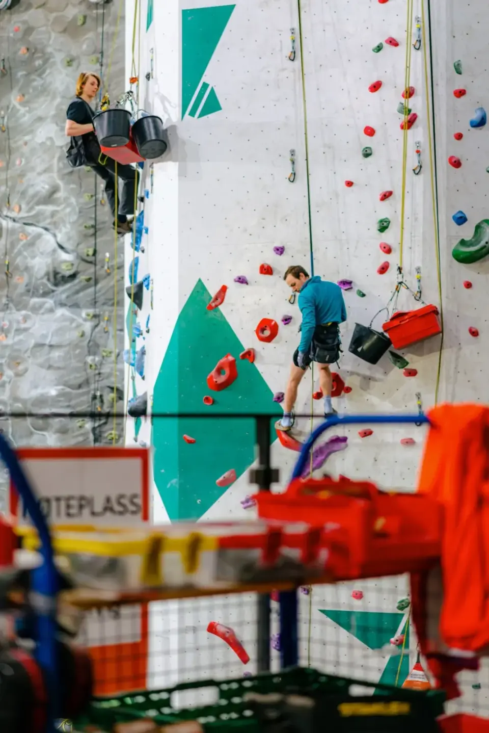 Route setters hanging on ropes while setting new routes on the tall walls