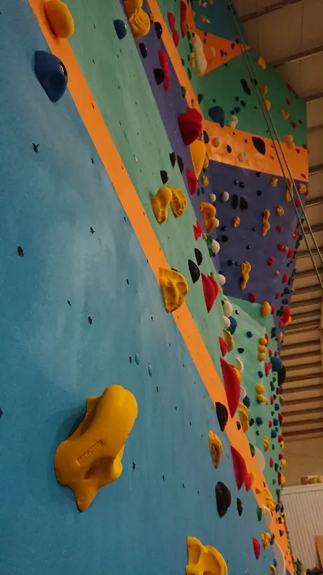 Looking up the roped wall past large yellow, red and blue holds