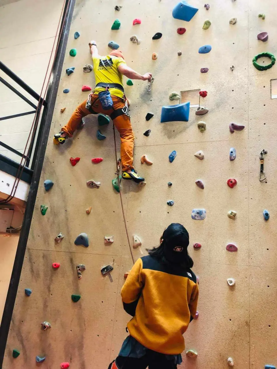 Climber halfway up the wall with a belayer at the bottom