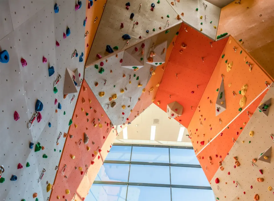 Looking up between angled climbing walls towards the hall's high windows
