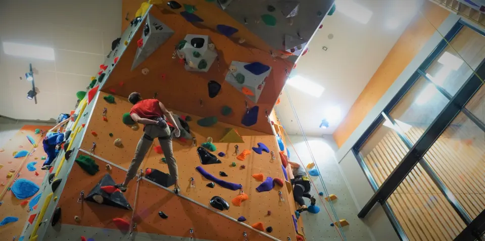 Climbers on roped routes up the orange and grey walls beside the windows