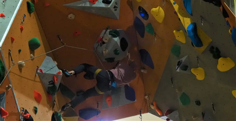 Climber on a steep section with large grey volumes, seen from below