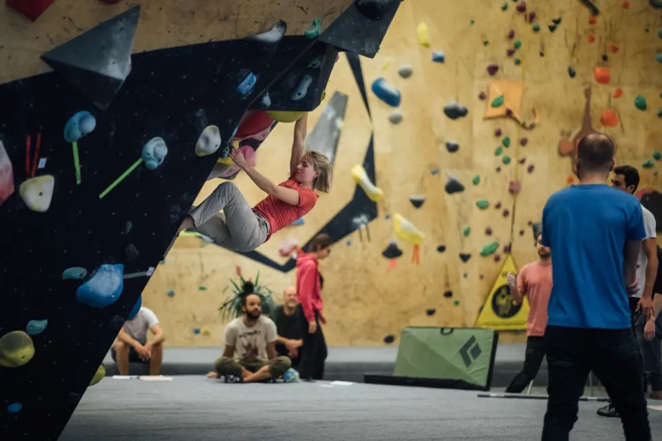 Climber hanging from a steep black overhang during a bouldering session