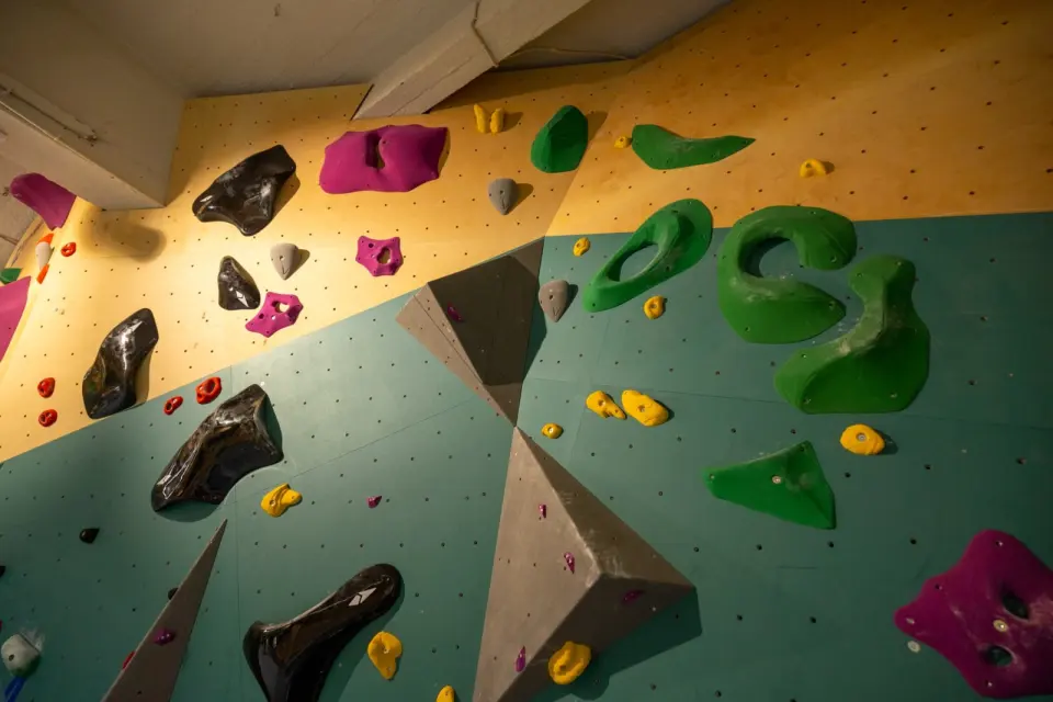 Bouldering wall with large green and black holds and grey volumes at Moss Klatresenter