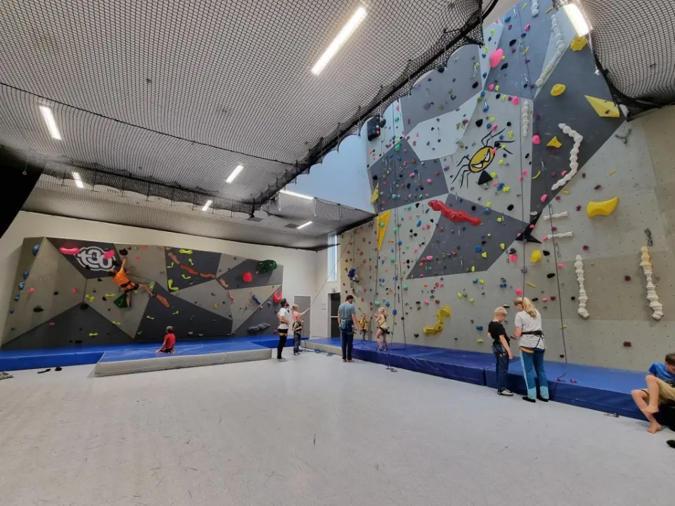 Climbing hall with a bouldering wall on the left and a tall roped wall on the right