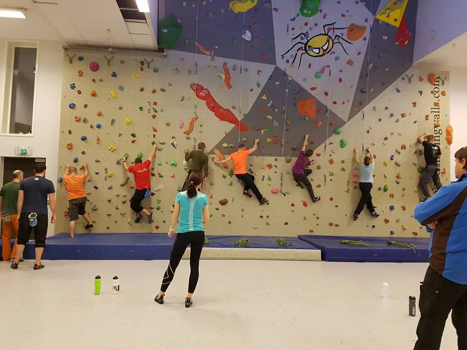 Row of climbers traversing the bottom of the roped wall above blue mats