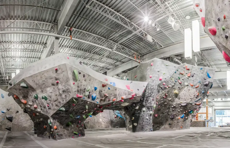 Large grey boulder features with overhangs and colourful holds above deep matting
