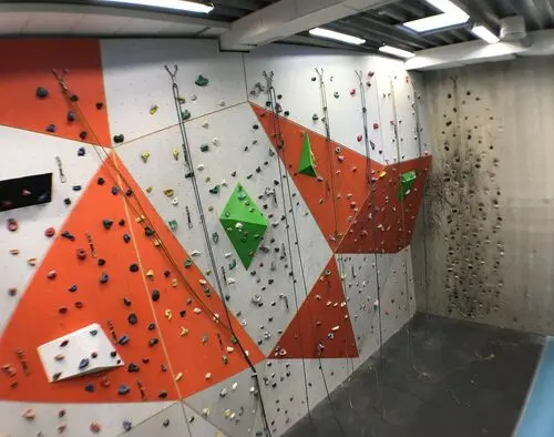 Roped climbing wall with orange and white panels and green volumes