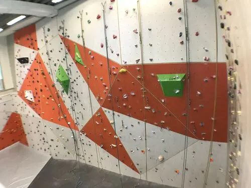 Top-rope lines hanging down the orange and white climbing wall