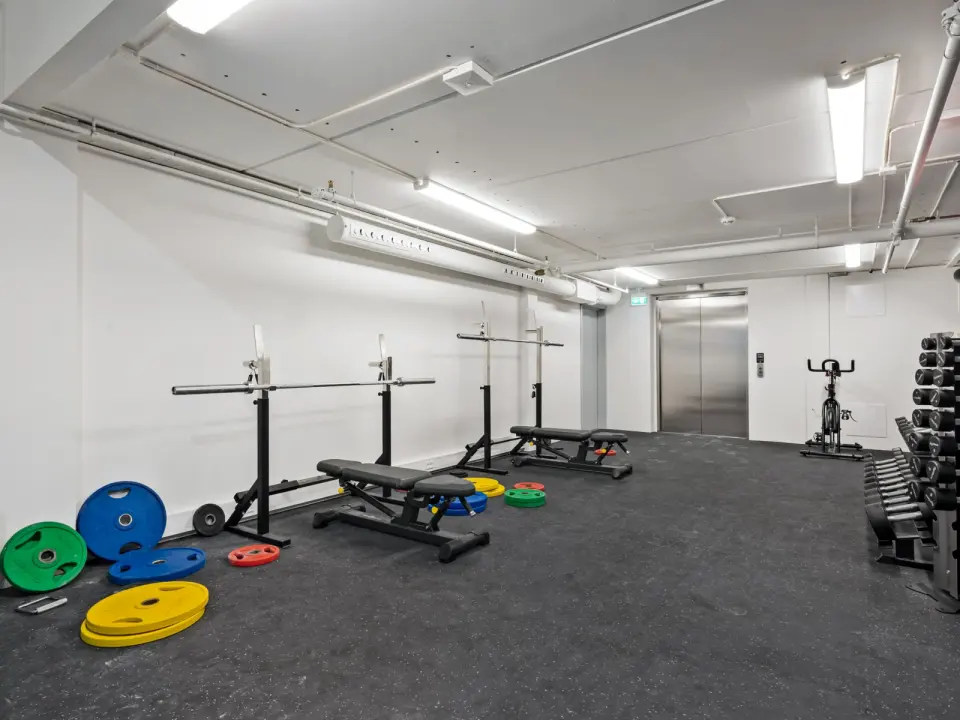 Strength room with squat racks, benches, weight plates and dumbbells