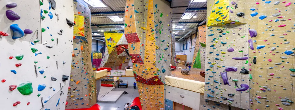 Indoor bouldering area with tall angled walls covered in colourful holds