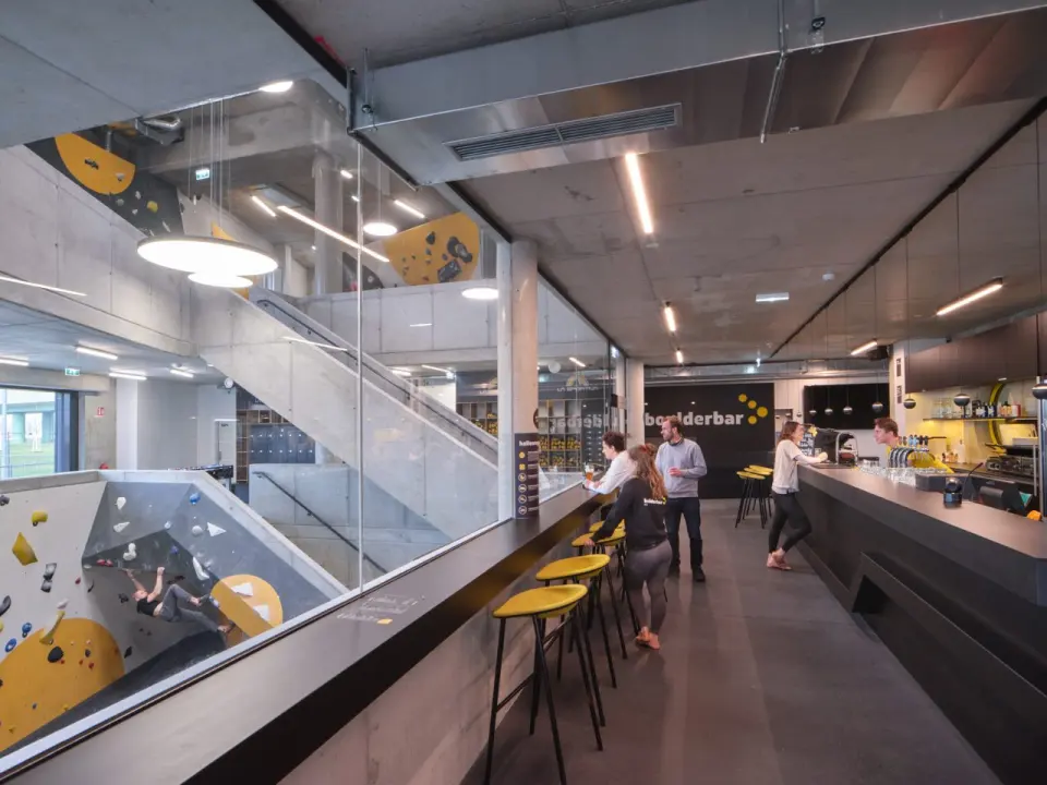 Bar overlooking the bouldering hall through a glass wall