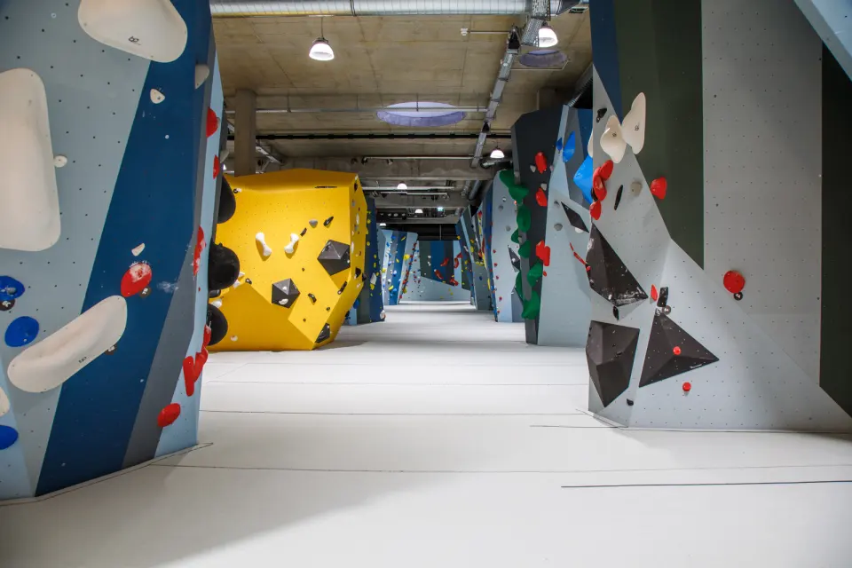 Long bouldering hall with blue walls and a large yellow volume