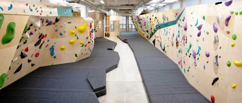 Long bouldering hall with walls on both sides of a matted walkway