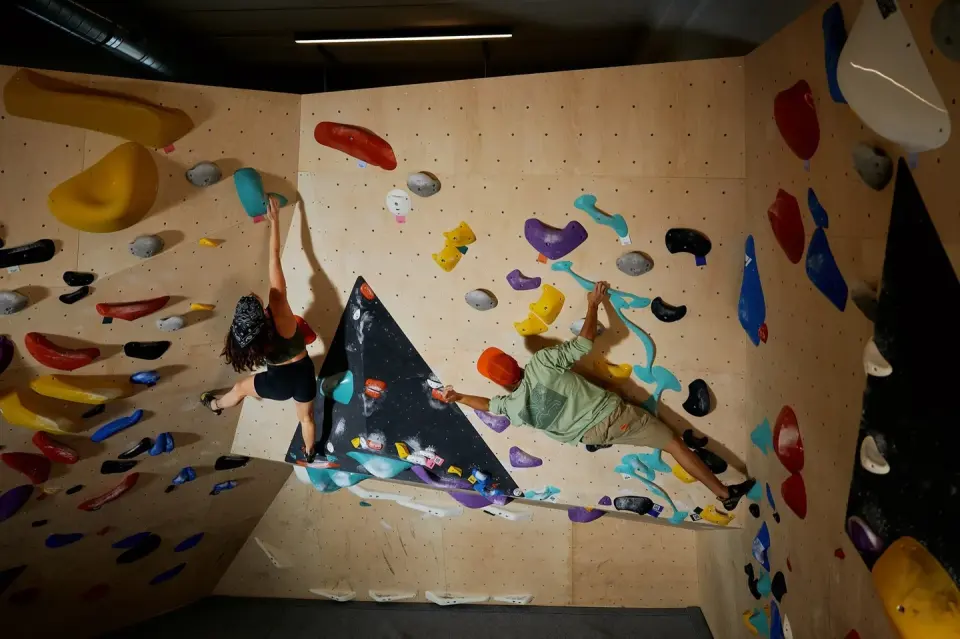 Two climbers on a steep wooden wall with large volumes
