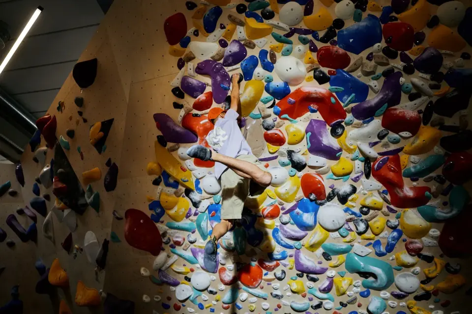 Climber on a spray wall packed with holds of every colour