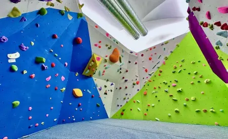 Bouldering room with blue, white and green walls set with holds