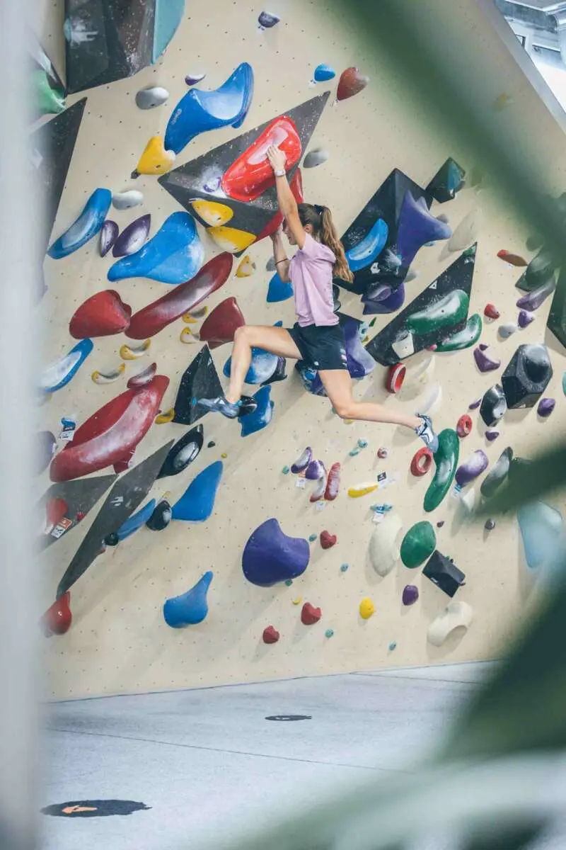 Climber reaching between red and blue volumes on a steep wall