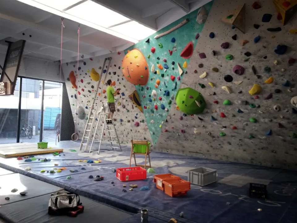Bouldering walls with large volumes and crates of holds on the mats during a reset