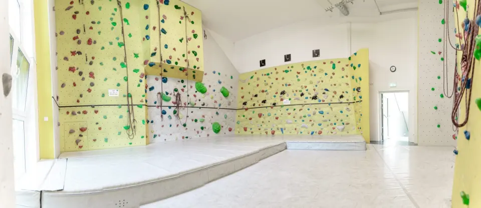 Wide view of a bright room with yellow climbing walls and ropes