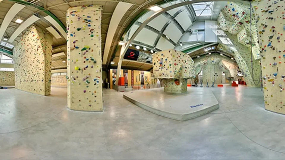 Wide view of the hall with tall lead walls and a bouldering block on a raised mat