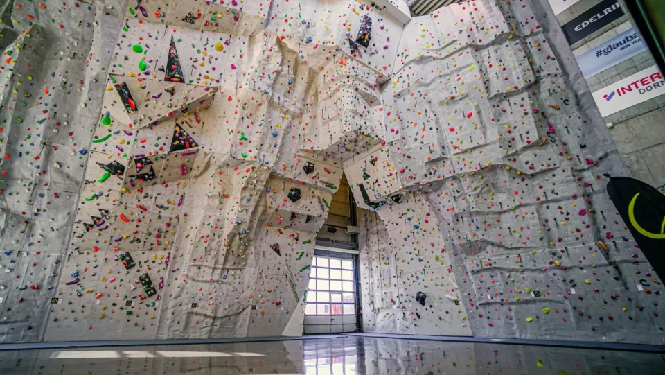 Huge overhanging lead wall covered in colourful holds above a shiny hall floor