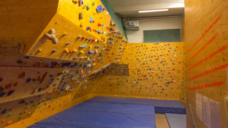 Bouldering room with wooden walls, an overhang and blue crash mats